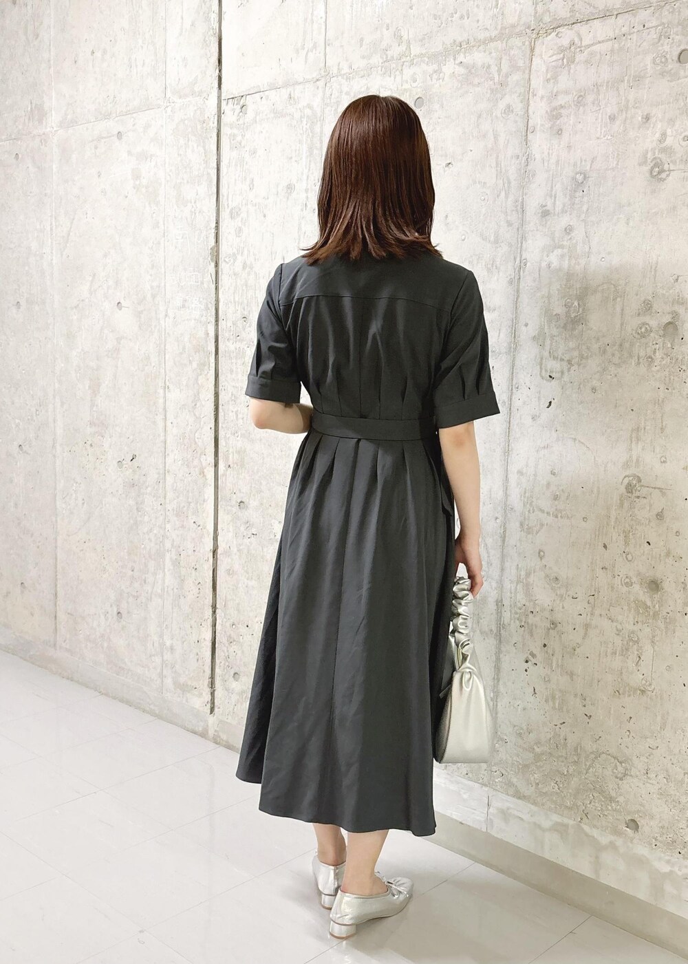 シルバー系のパンプス、グレー系のシャツワンピース、シルバー系のハンドバッグを着用したレディースの夏コーディネートの4枚目の写真