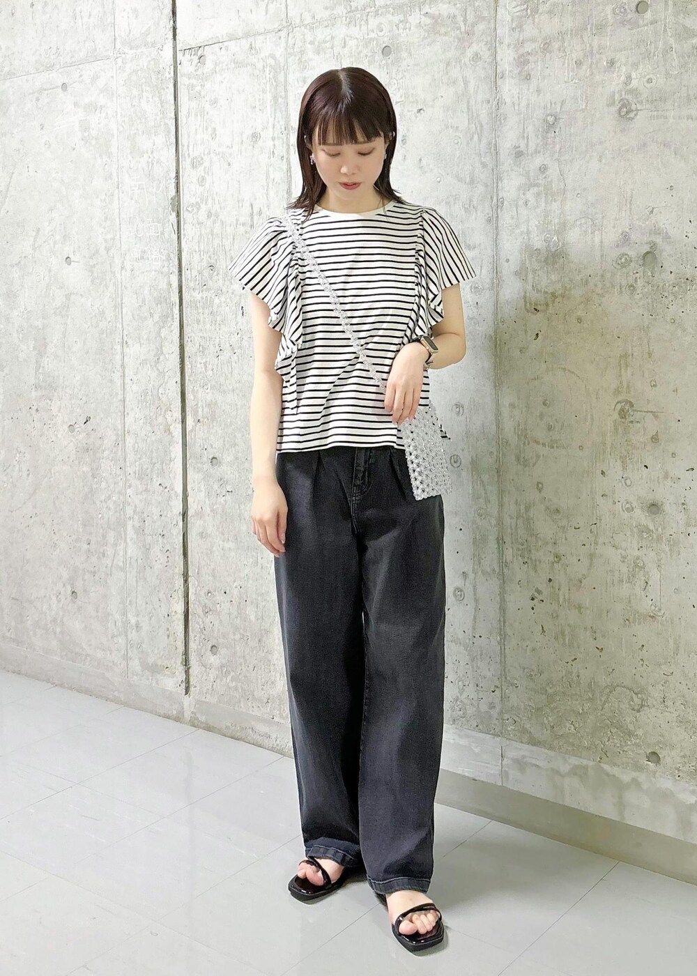 ブラック系のサンダル、ホワイト系のショルダーバッグ、ホワイト系のTシャツ/カットソーを着用したレディースの春コーディネートの2枚目の写真