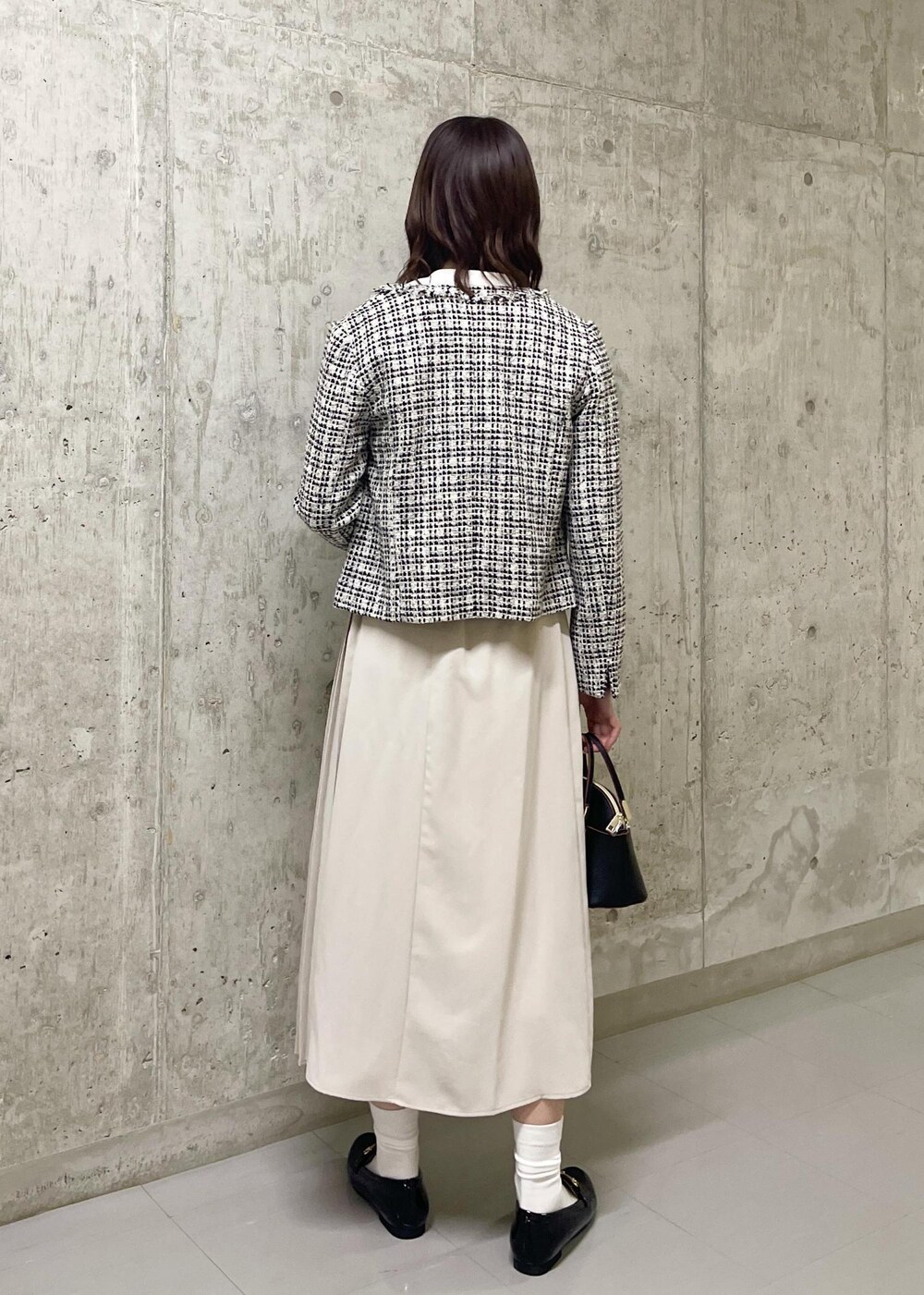 ブラック系のローファー、ブラック系のノーカラージャケット、ブラック系のショルダーバッグを着用したレディースの春コーディネートの4枚目の写真