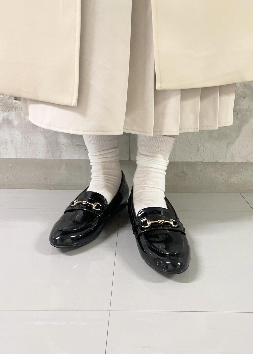 ブラック系のローファー、ブラック系のショルダーバッグ、ベージュ系のスカートを着用したレディースの春コーディネートの5枚目の写真