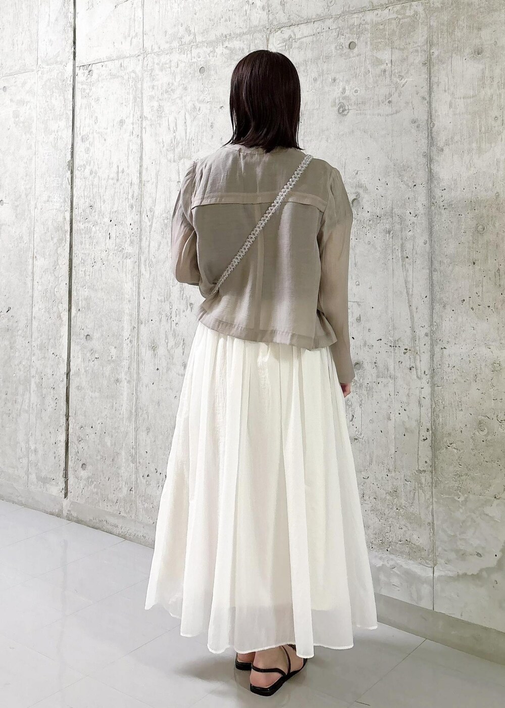 ホワイト系のスカート、ベージュ系のカーディガン/ボレロ、ブラック系のTシャツ/カットソーを着用したレディースの夏コーディネートの3枚目の写真