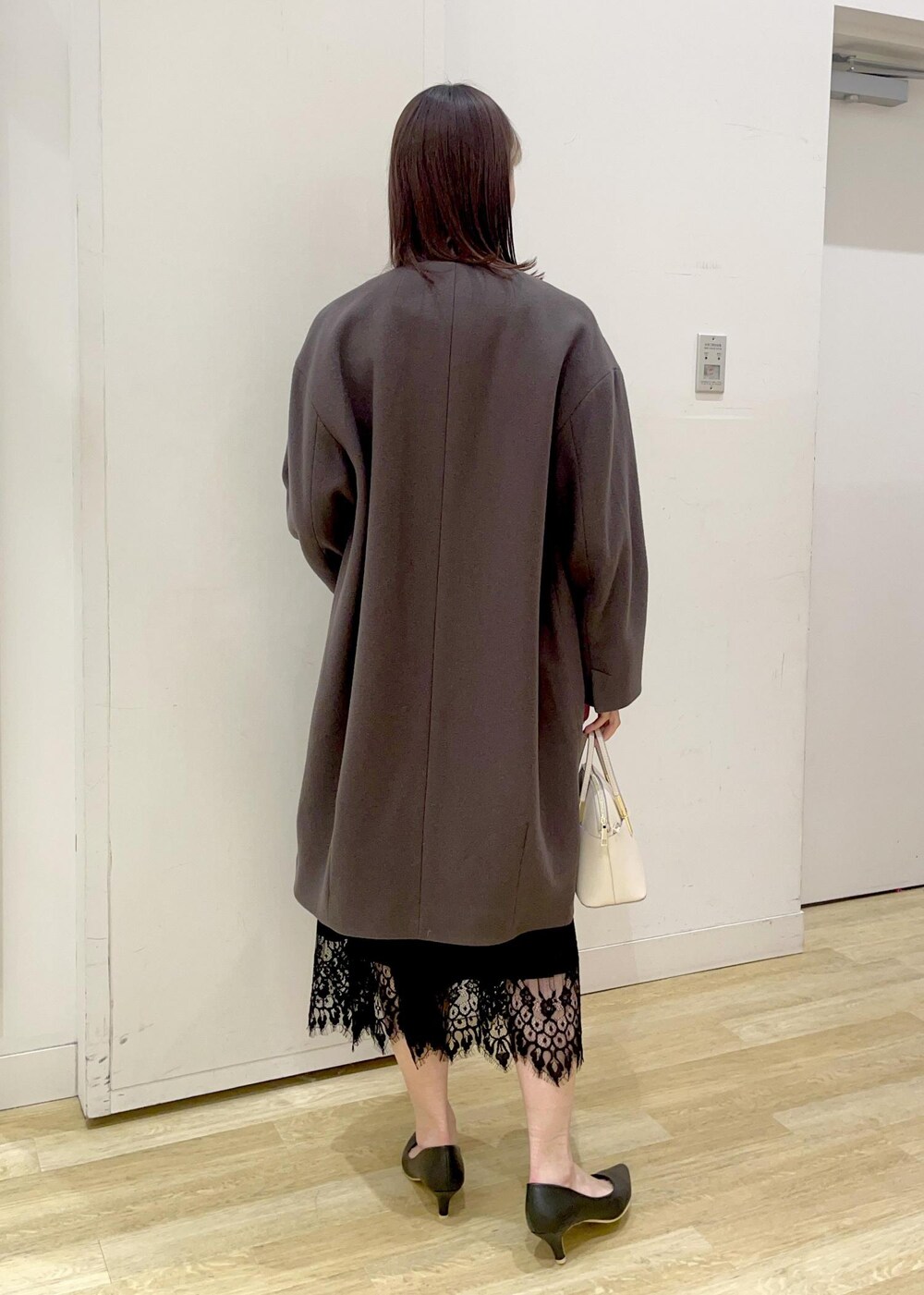 ブラック系のドレス、ブラック系のパンプス、ホワイト系のショルダーバッグを着用したレディースの冬コーディネートの3枚目の写真