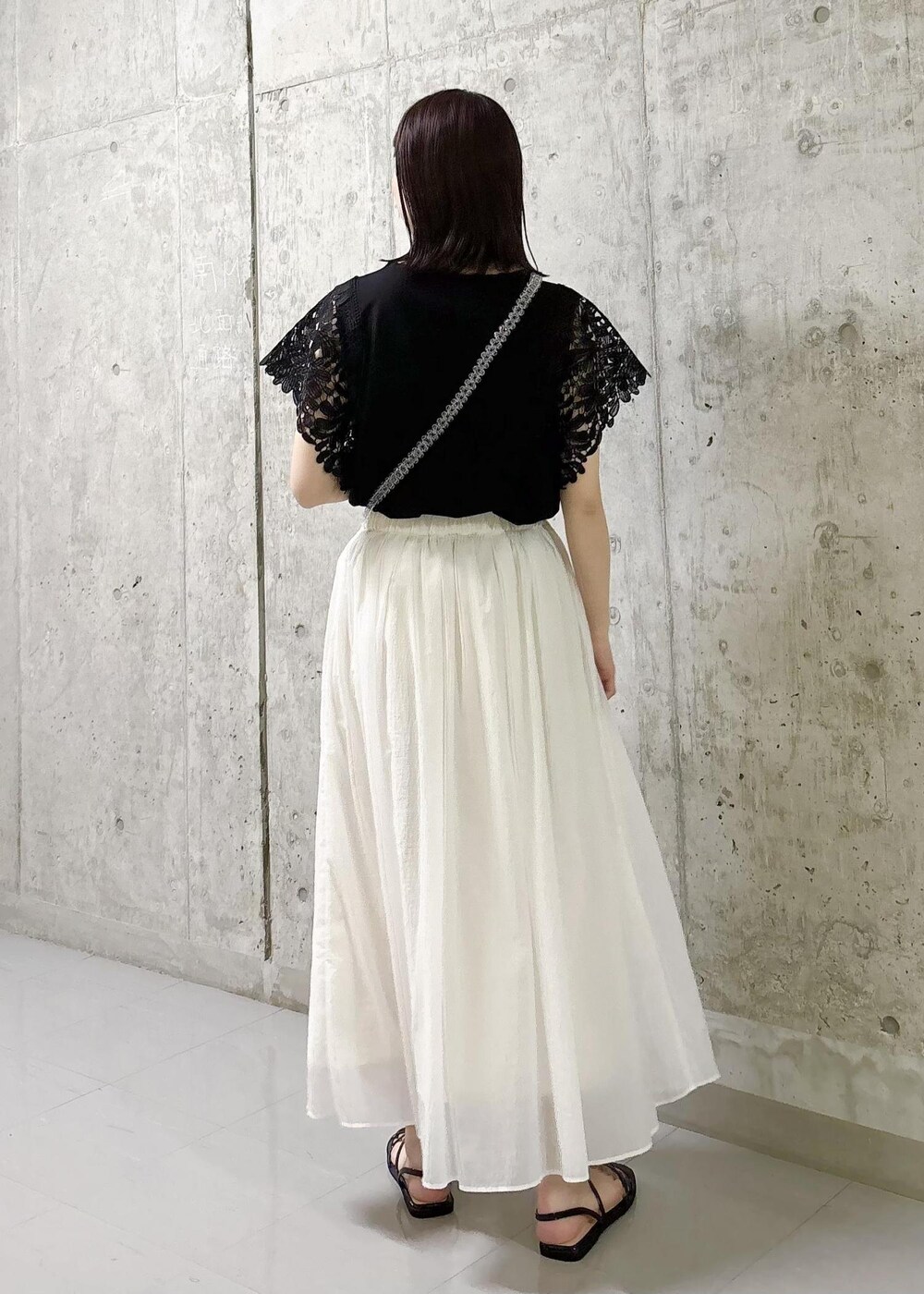 ホワイト系のスカート、ブラック系のTシャツ/カットソー、ブラック系のサンダルを着用したレディースの夏コーディネートの3枚目の写真