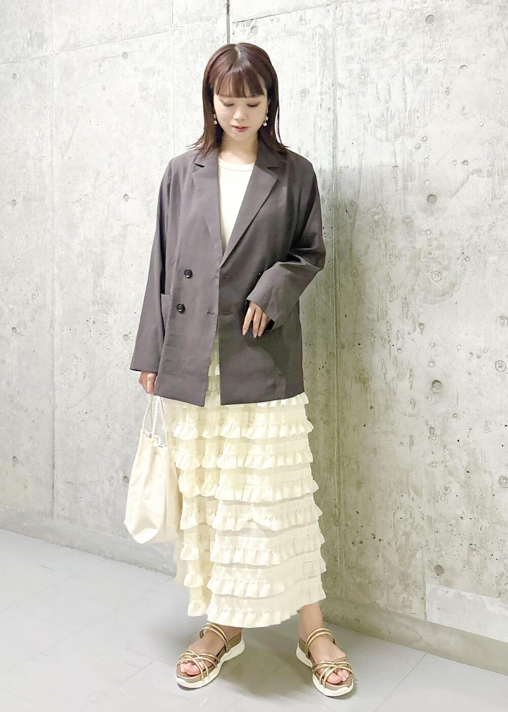 ホワイト系のワンピース、ゴールド系のサンダル、ブラウン系のテーラードジャケットを着用したレディースの夏コーディネートの2枚目の写真