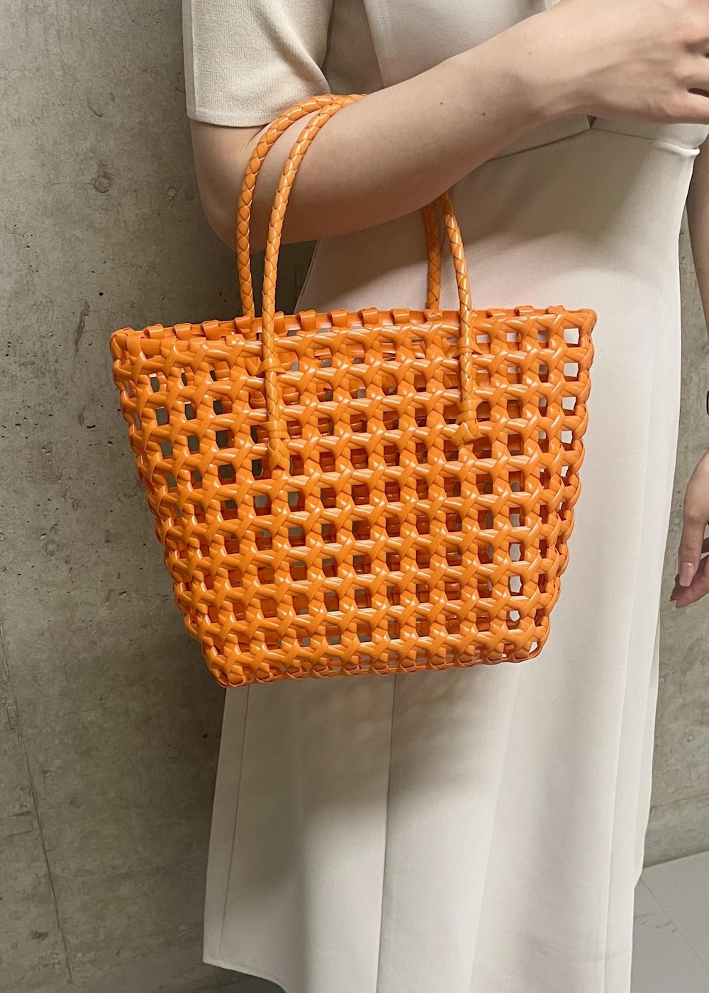 オレンジ系のトートバッグ、ホワイト系のローファー、ホワイト系のニット/セーターを着用したレディースの夏コーディネートの6枚目の写真