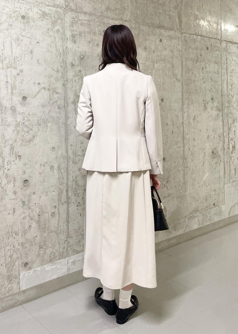 イエロー系のテーラードジャケット、ブラック系のローファー、ブラック系のショルダーバッグを着用したレディースの春コーディネートの3枚目の写真