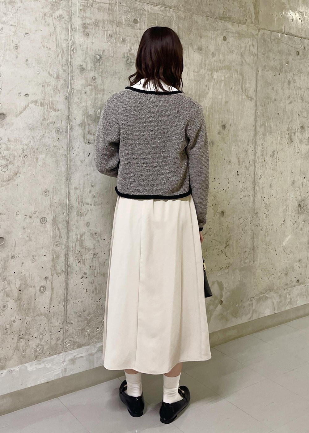 ブラック系のローファー、ブラック系のショルダーバッグ、ベージュ系のスカートを着用したレディースの春コーディネートの3枚目の写真