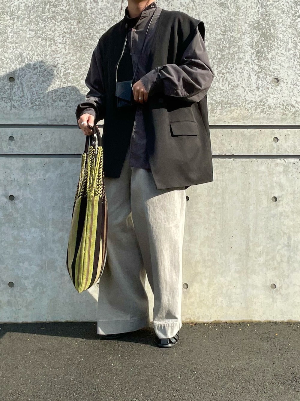 グレー系のデニムパンツ、ブラック系のニット/セーター、ブラック系のベストを着用したメンズの冬コーディネートの2枚目の写真