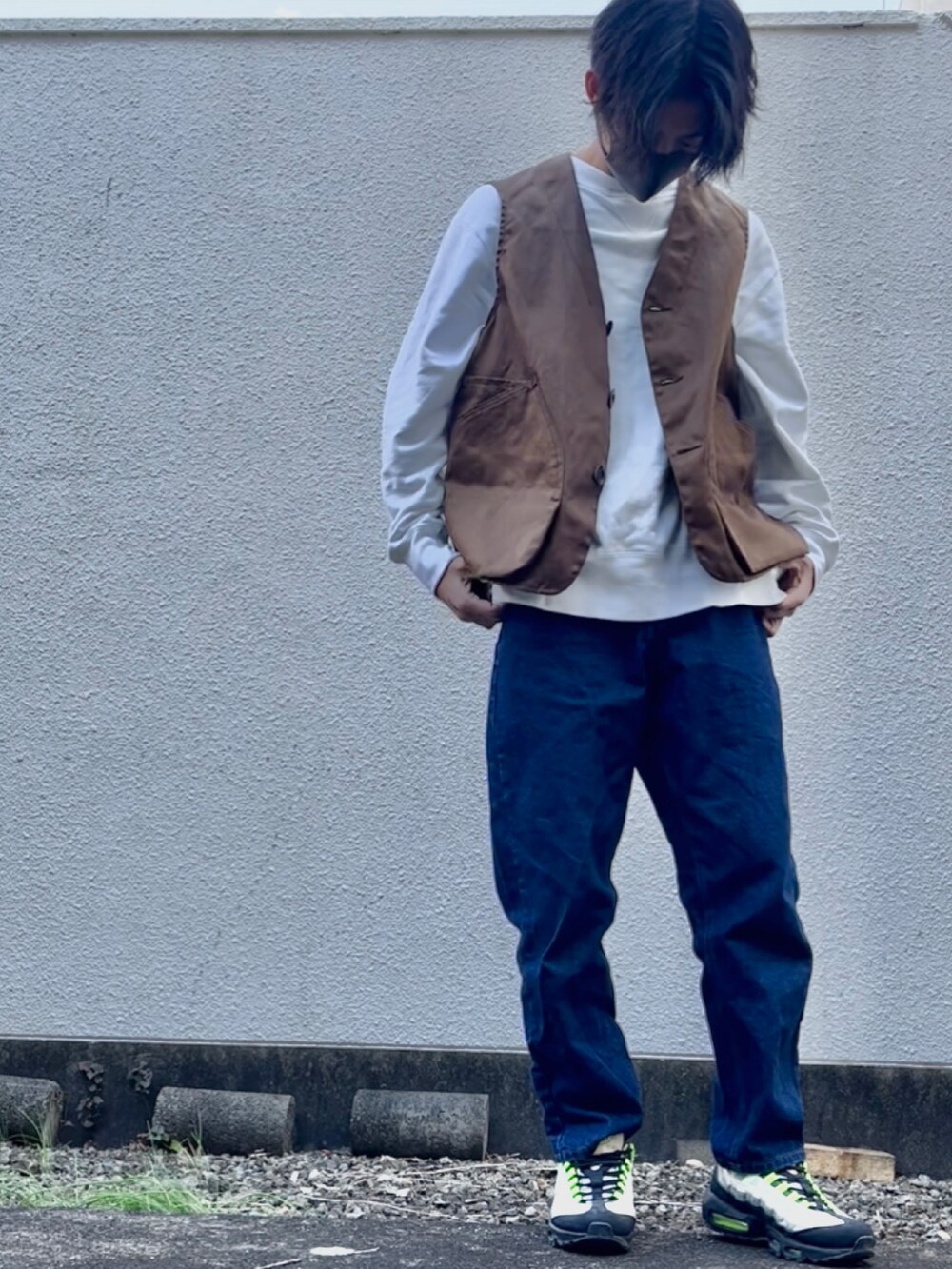 ブルー系のデニムパンツ、ホワイト系のスウェット、ブラウン系のベストを着用したメンズの秋コーディネートの2枚目の写真