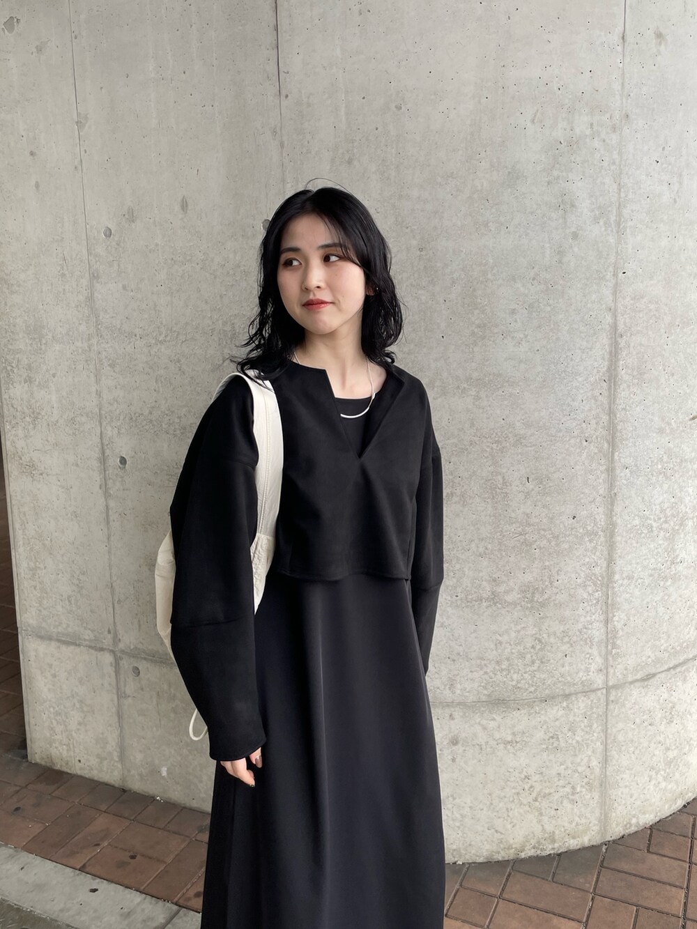 ブラック系のワンピース、ホワイト系のショルダーバッグを着用したレディースの秋コーディネートの2枚目の写真