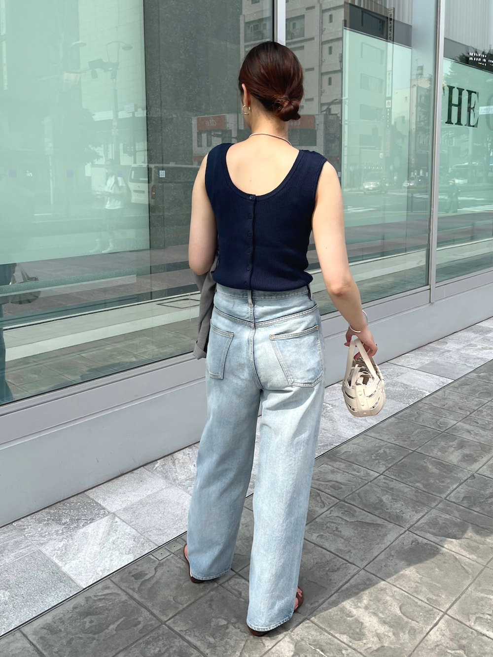 ブルー系のニット/セーター、ブルー系のデニムパンツ、ホワイト系のトートバッグを着用したレディースの夏コーディネートの2枚目の写真