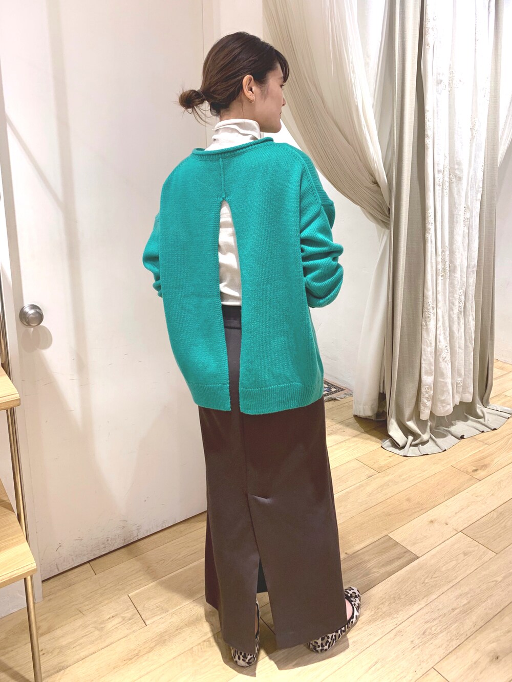 グレー系のスカート、グリーン系のニット/セーター、ベージュ系のTシャツ/カットソーを着用したレディースの秋コーディネートの2枚目の写真