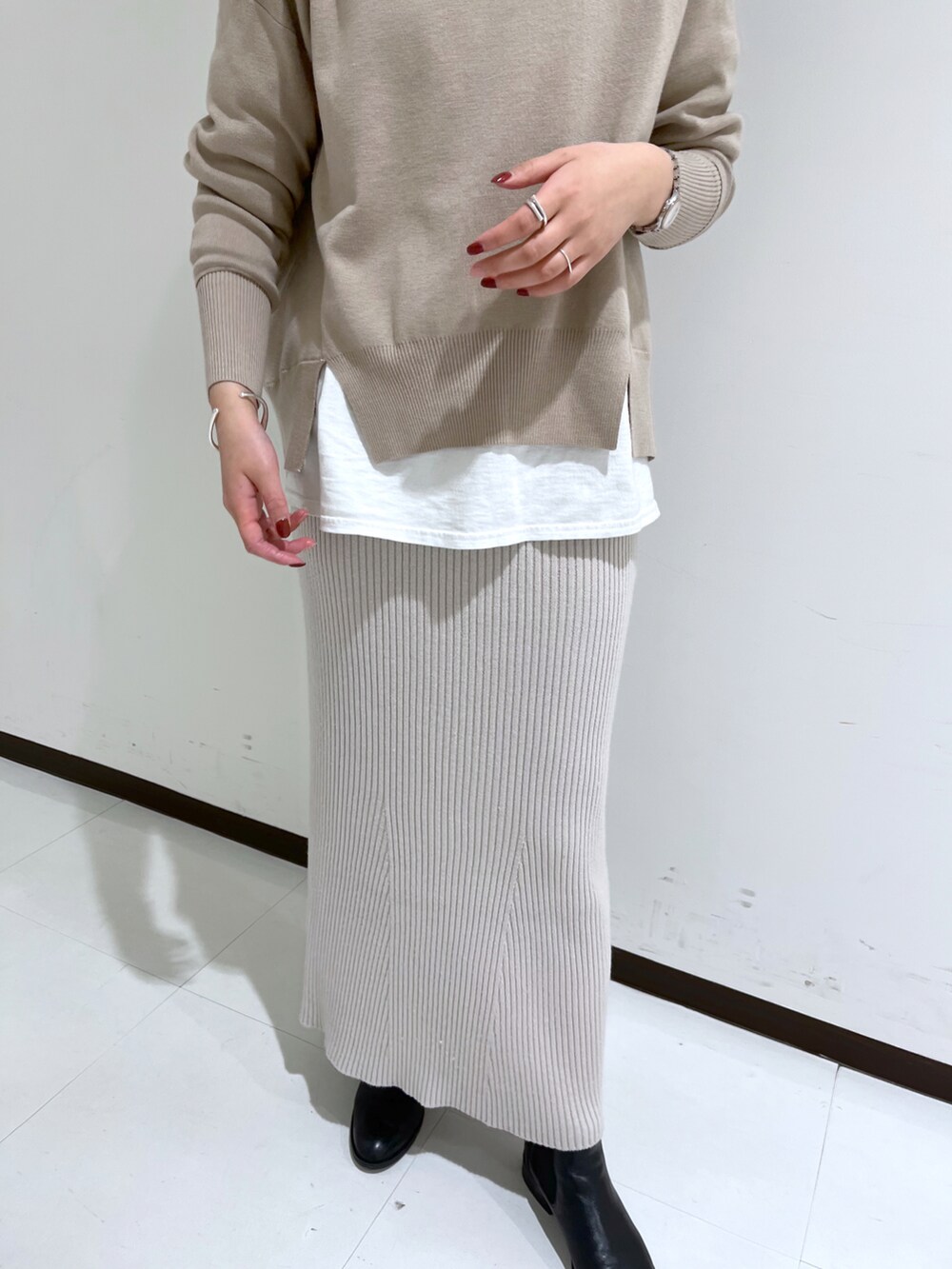 グレー系のスカート、ブラウン系のニット/セーター、シルバー系のネックレスを着用したレディースの冬コーディネートの3枚目の写真