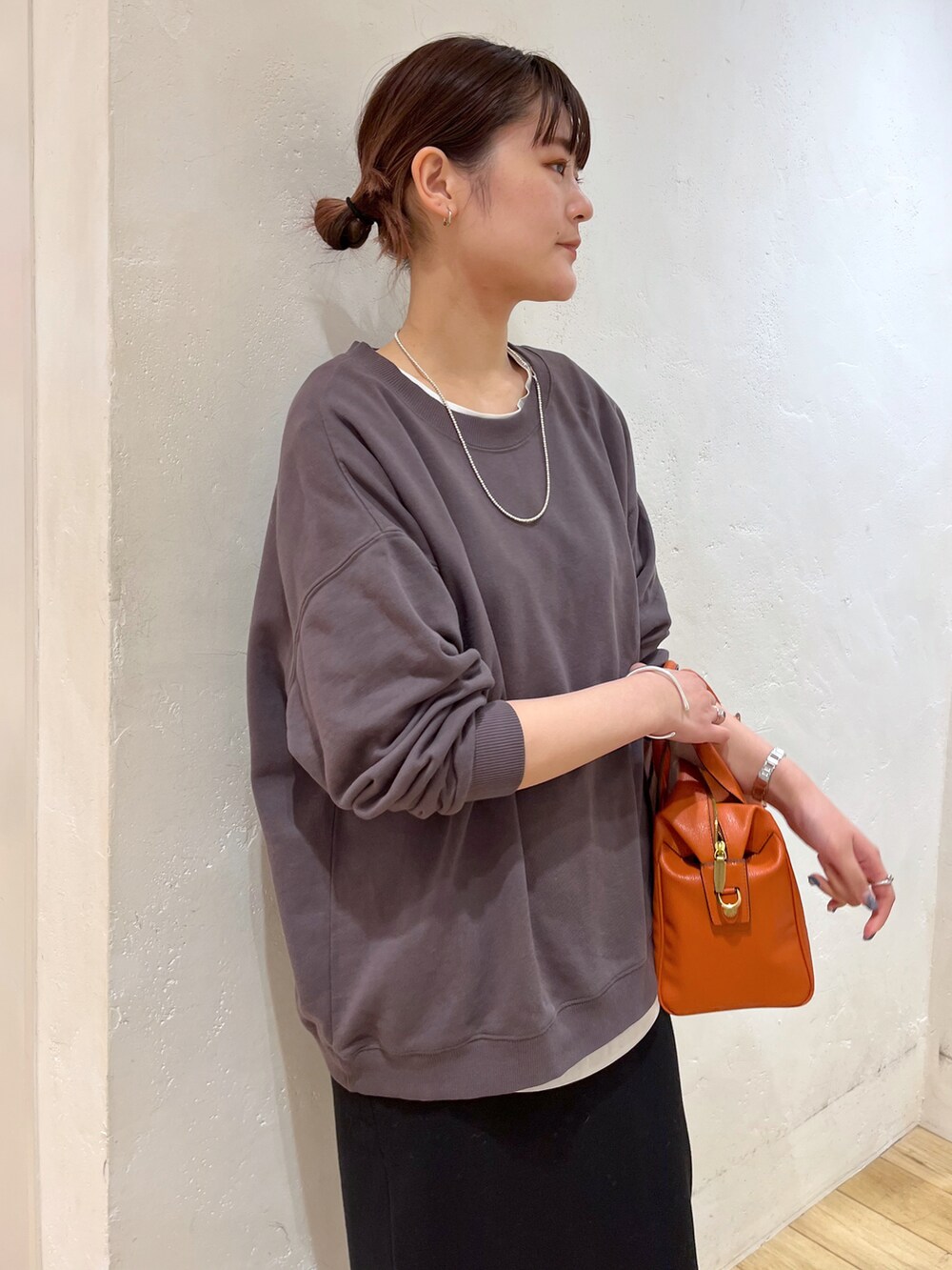 グレー系のTシャツ/カットソー、ブラック系のスカート、オレンジ系のボストンバッグを着用したレディースの冬コーディネートの3枚目の写真