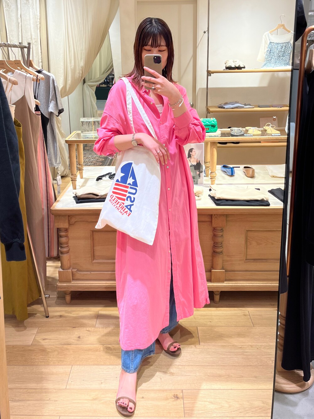 ピンク系のワンピース、ホワイト系のトートバッグ、ブルー系のデニムパンツを着用したレディースの夏コーディネートの2枚目の写真