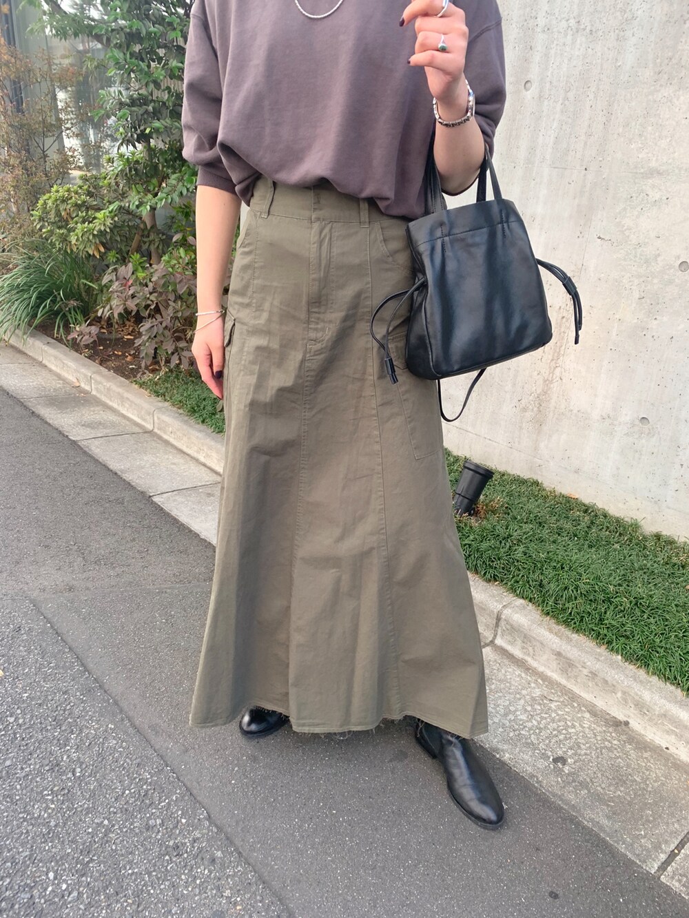 グレー系のTシャツ/カットソー、グリーン系のスカート、ブラック系のトートバッグを着用したレディースの秋コーディネートの3枚目の写真