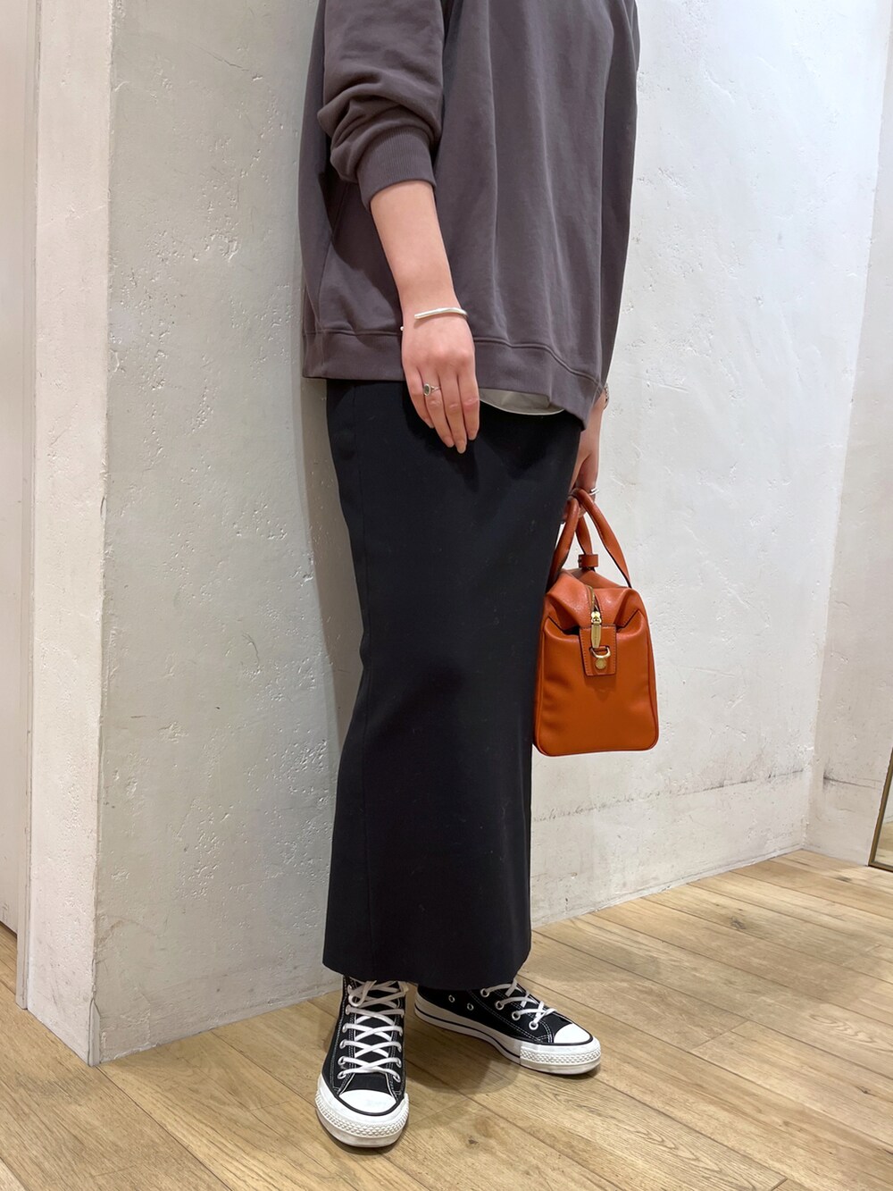 グレー系のTシャツ/カットソー、ブラック系のスカート、オレンジ系のボストンバッグを着用したレディースの冬コーディネートの2枚目の写真