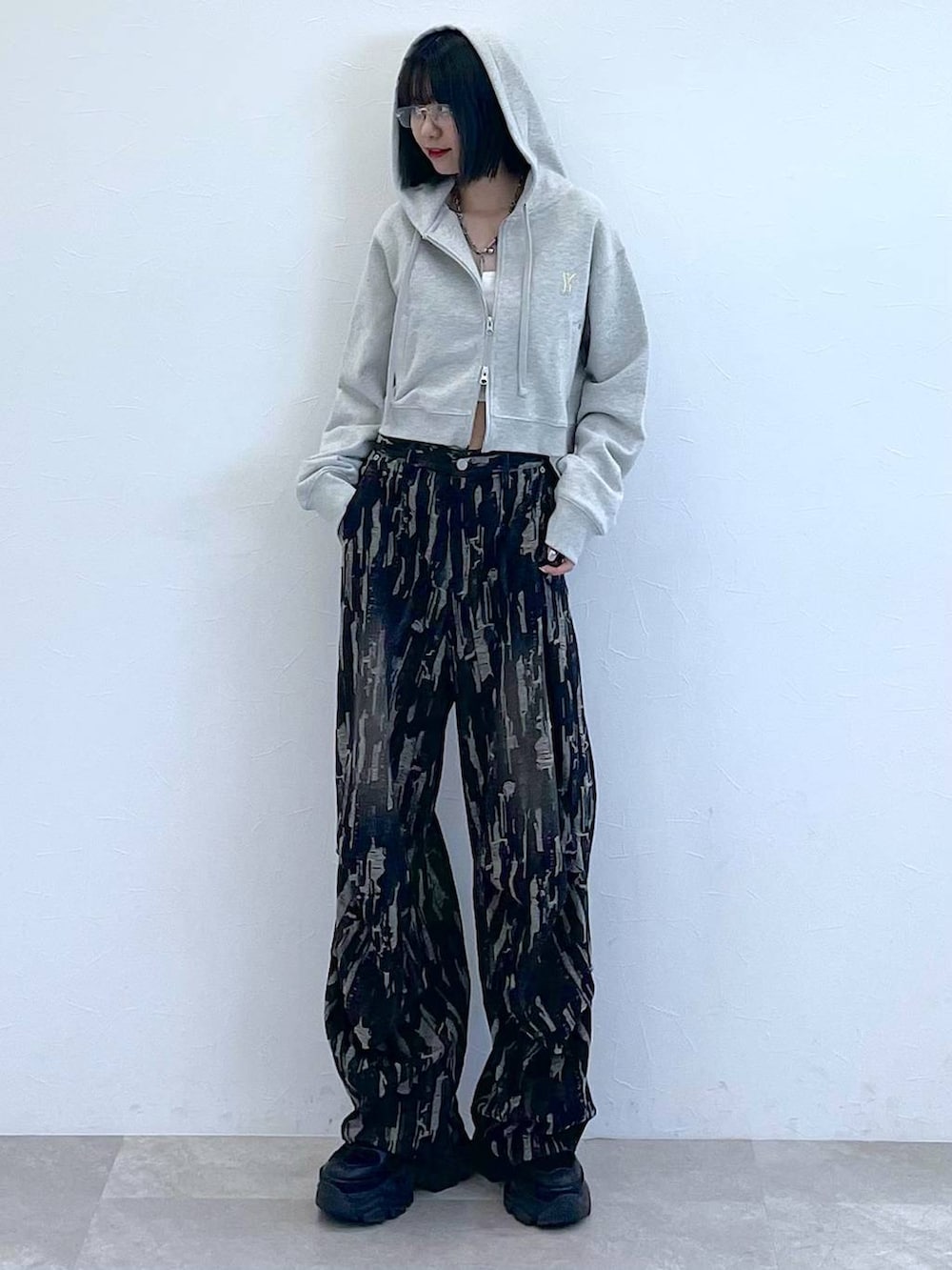 グレー系のパーカー、ホワイト系のキャミソール、ブラック系のスニーカーを着用したレディースの秋コーディネートの7枚目の写真