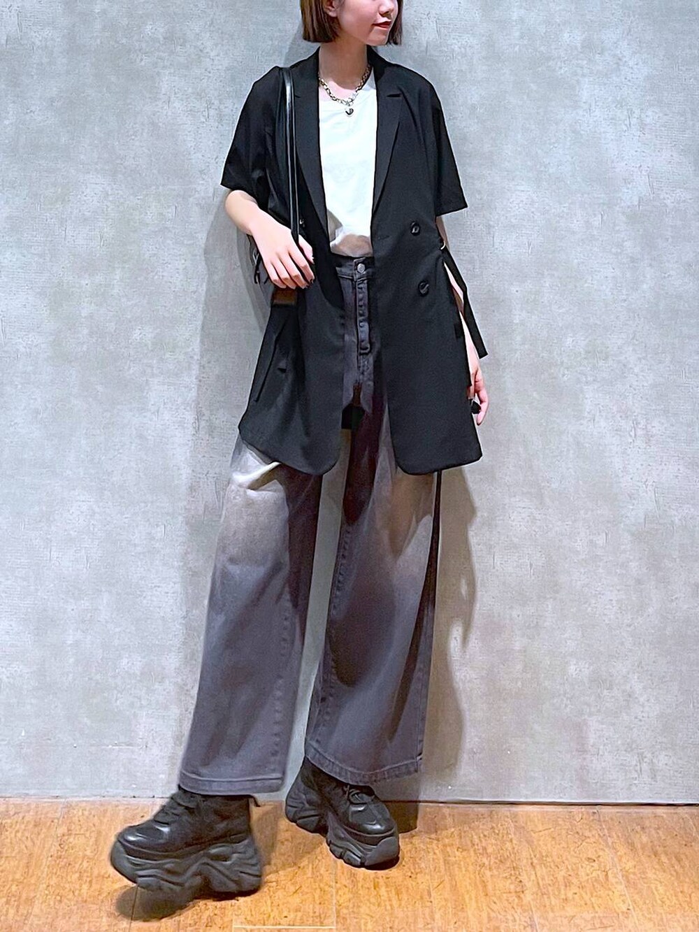 ブラック系のスニーカー、ホワイト系のTシャツ/カットソー、ブラック系のハンドバッグを着用したレディースの夏コーディネートの5枚目の写真