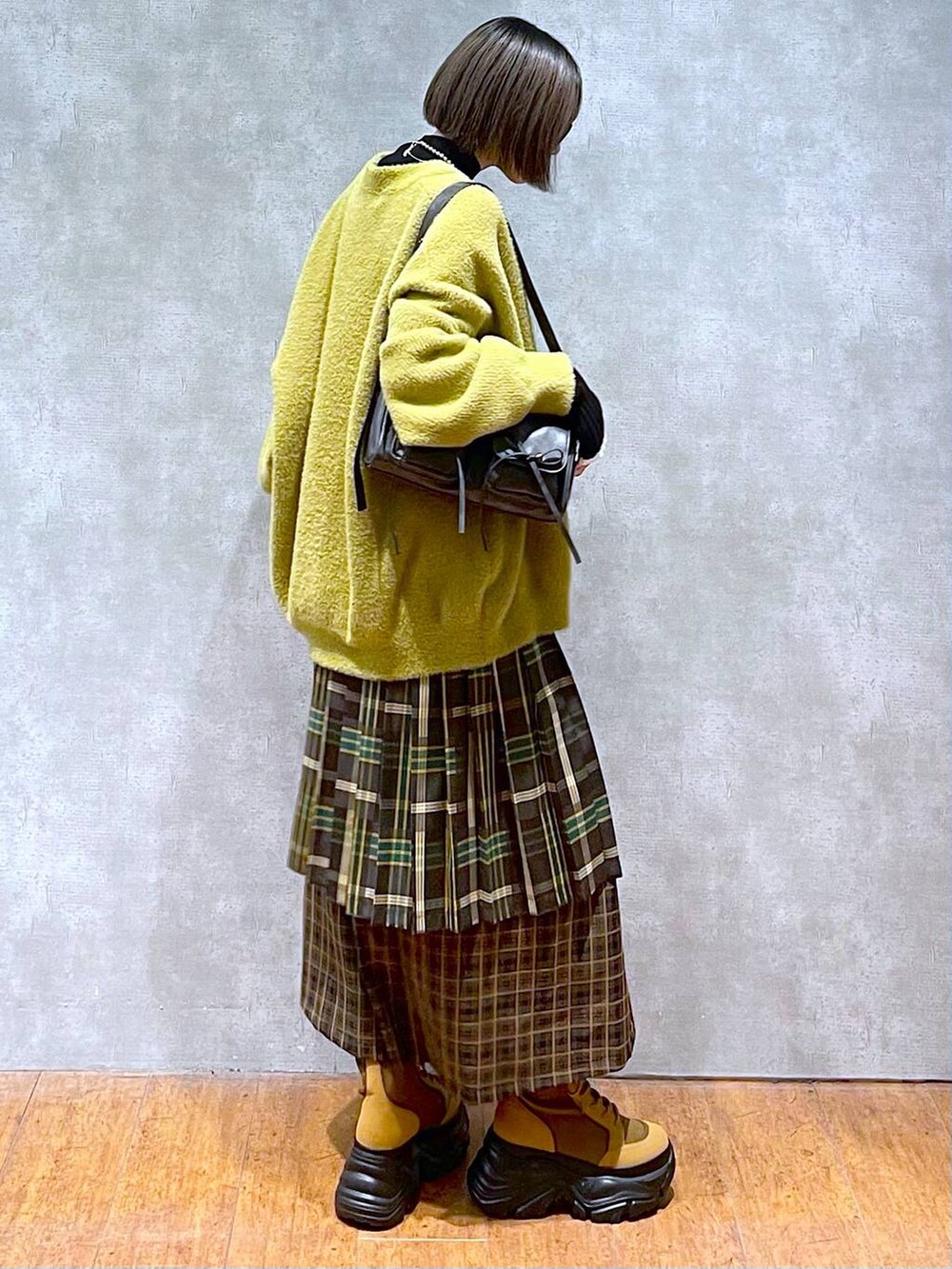 ブラック系のニット/セーター、ブラック系のショルダーバッグ、ブラウン系のブーツを着用したレディースの秋コーディネートの4枚目の写真