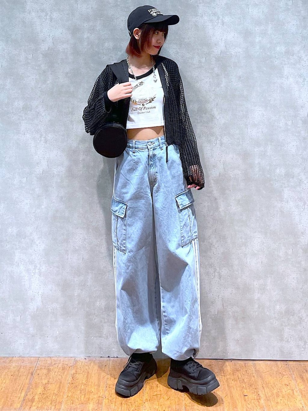 ブラック系のドラムバッグ、ホワイト系のTシャツ/カットソー、ブラック系のブーツを着用したレディースの春コーディネートの3枚目の写真