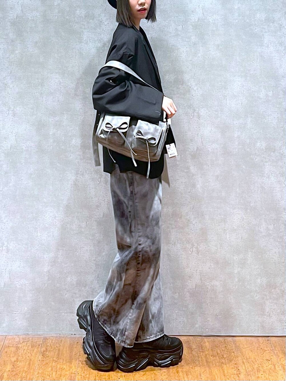 ブラック系のスニーカー、グレー系のショルダーバッグ、ブラック系のデニムパンツを着用したレディースの秋コーディネートの5枚目の写真