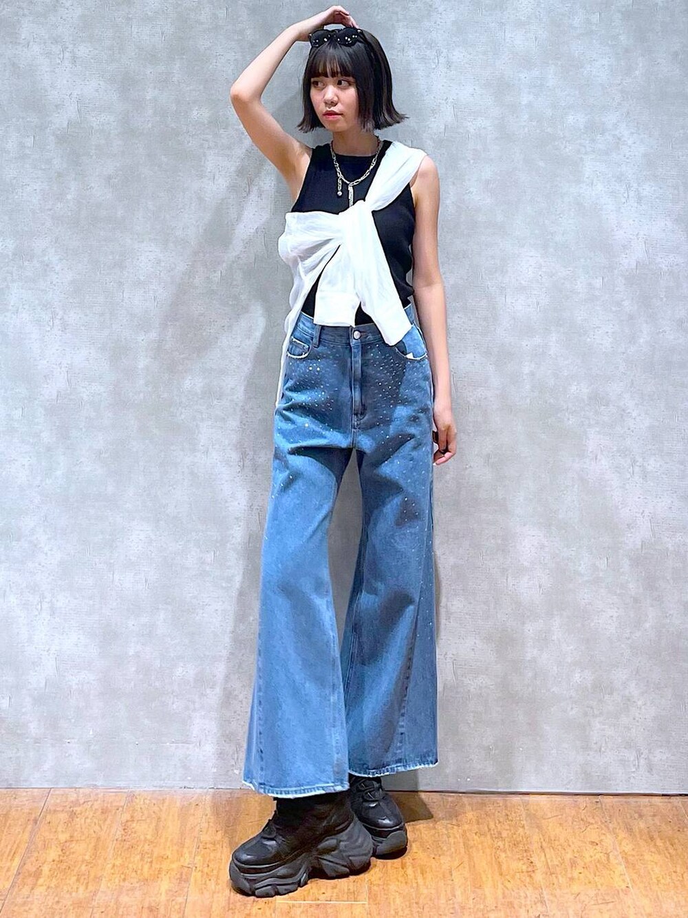 ブラック系のスニーカー、ブラック系のタンクトップ、ブルー系のデニムパンツを着用したレディースの夏コーディネートの6枚目の写真