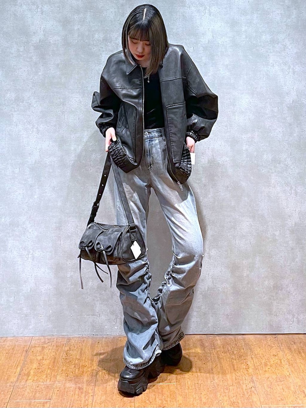 ブラック系のスニーカー、ブラック系のショルダーバッグ、ブルー系のデニムパンツを着用したレディースの秋コーディネートの3枚目の写真