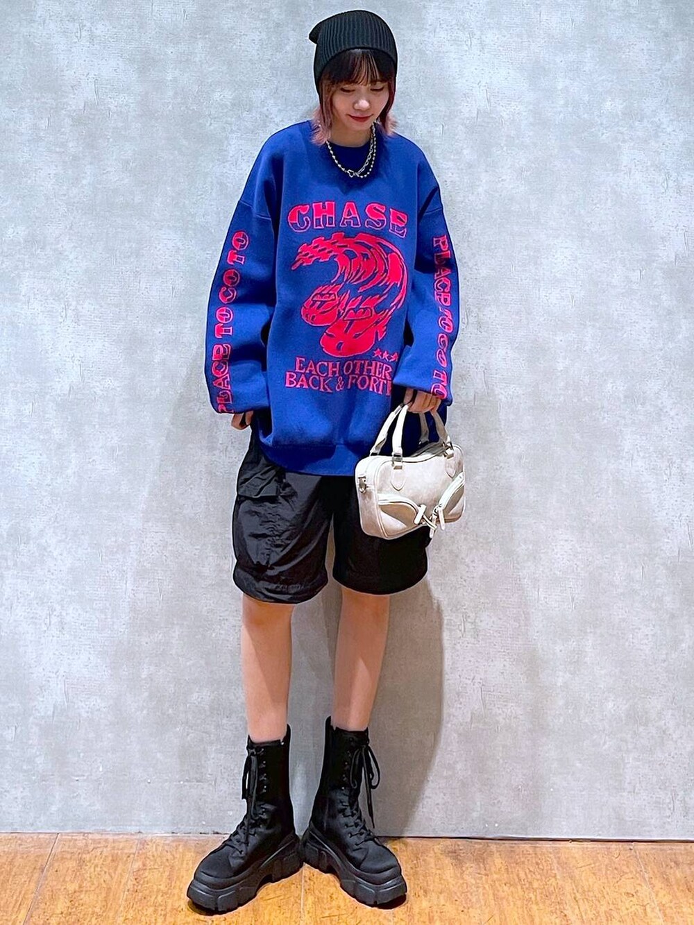 ブラック系のカーゴパンツ、ブルー系のニット/セーター、ベージュ系のボストンバッグを着用したレディースの冬コーディネートの3枚目の写真