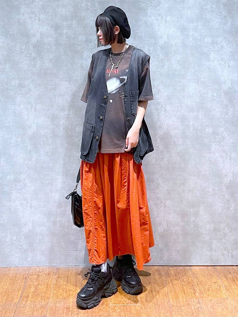 ブラック系のスニーカー、ブラック系のショルダーバッグ、オレンジ系のスカートを着用したレディースの夏コーディネートの6枚目の写真