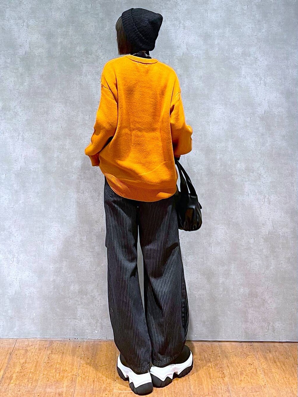 ブラック系のニット/セーター、ブラック系のデニムパンツ、ブラック系のハンドバッグを着用したレディースの秋コーディネートの4枚目の写真