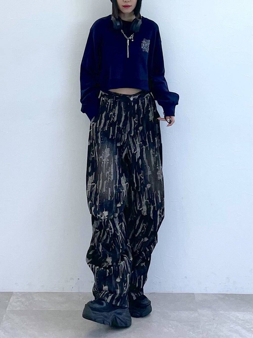 ブラック系のスニーカー、ブラック系のデニムパンツ、ホワイト系のキャミソールを着用したレディースの秋コーディネートの3枚目の写真