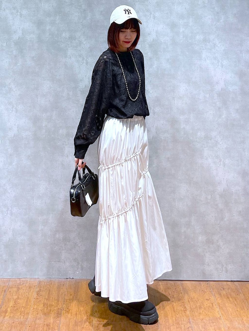 ブラック系のシャツ/ブラウス、ホワイト系のスカート、ブラック系のボストンバッグを着用したレディースの春コーディネートの5枚目の写真