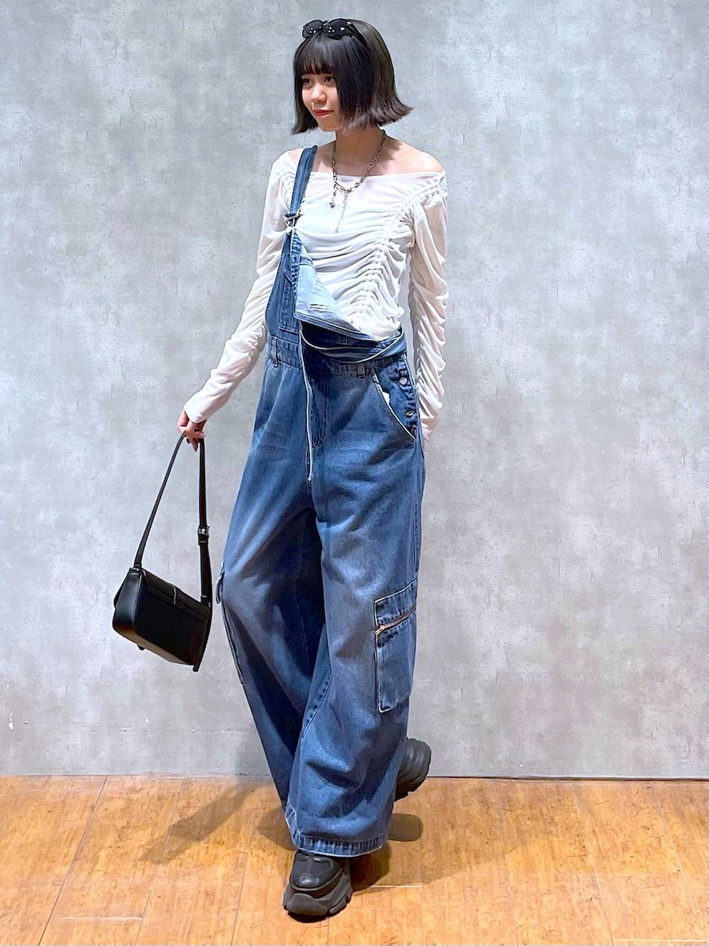 ブラック系のスニーカー、ブラック系のハンドバッグ、ブルー系のサロペット/オーバーオールを着用したレディースの夏コーディネートの2枚目の写真