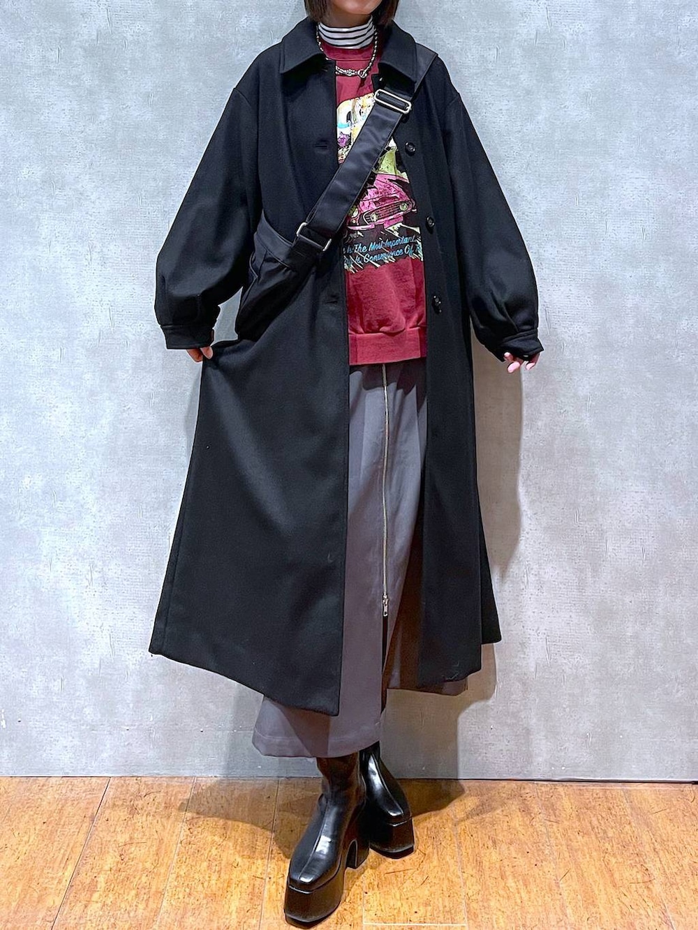 グレー系のスカート、ブラック系のチェスターコート、ブラック系のブーツを着用したレディースの冬コーディネートの5枚目の写真