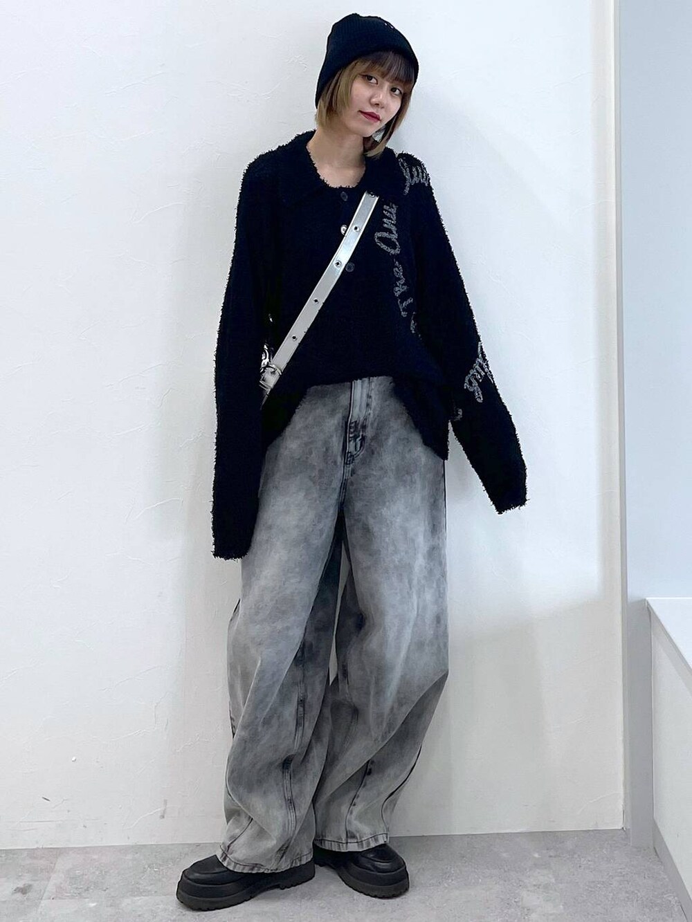 シルバー系のショルダーバッグ、ブラック系のブーツ、ブラック系のデニムパンツを着用したレディースの冬コーディネートの3枚目の写真