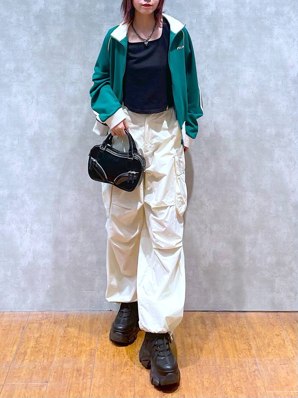 グリーン系のセットアップ、ブラック系のボストンバッグ、ホワイト系のカーゴパンツを着用したレディースの春コーディネートの4枚目の写真
