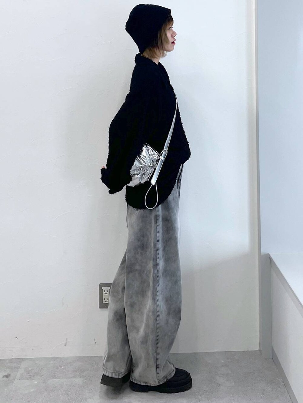 シルバー系のショルダーバッグ、ブラック系のブーツ、ブラック系のデニムパンツを着用したレディースの冬コーディネートの5枚目の写真
