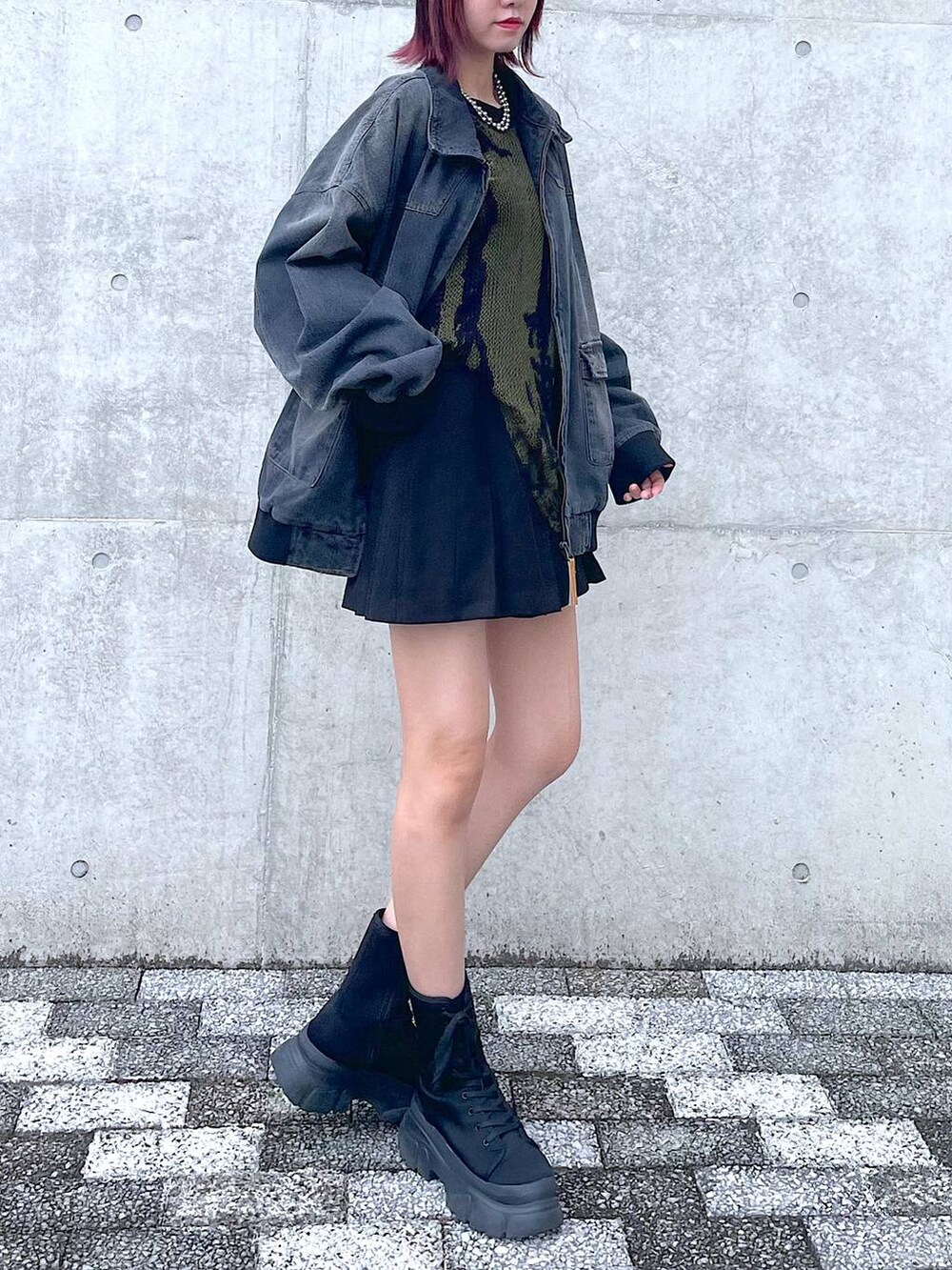 ブラック系のデニムジャケット、グリーン系のニット/セーター、ブラック系のその他パンツを着用したレディースの春コーディネートの2枚目の写真