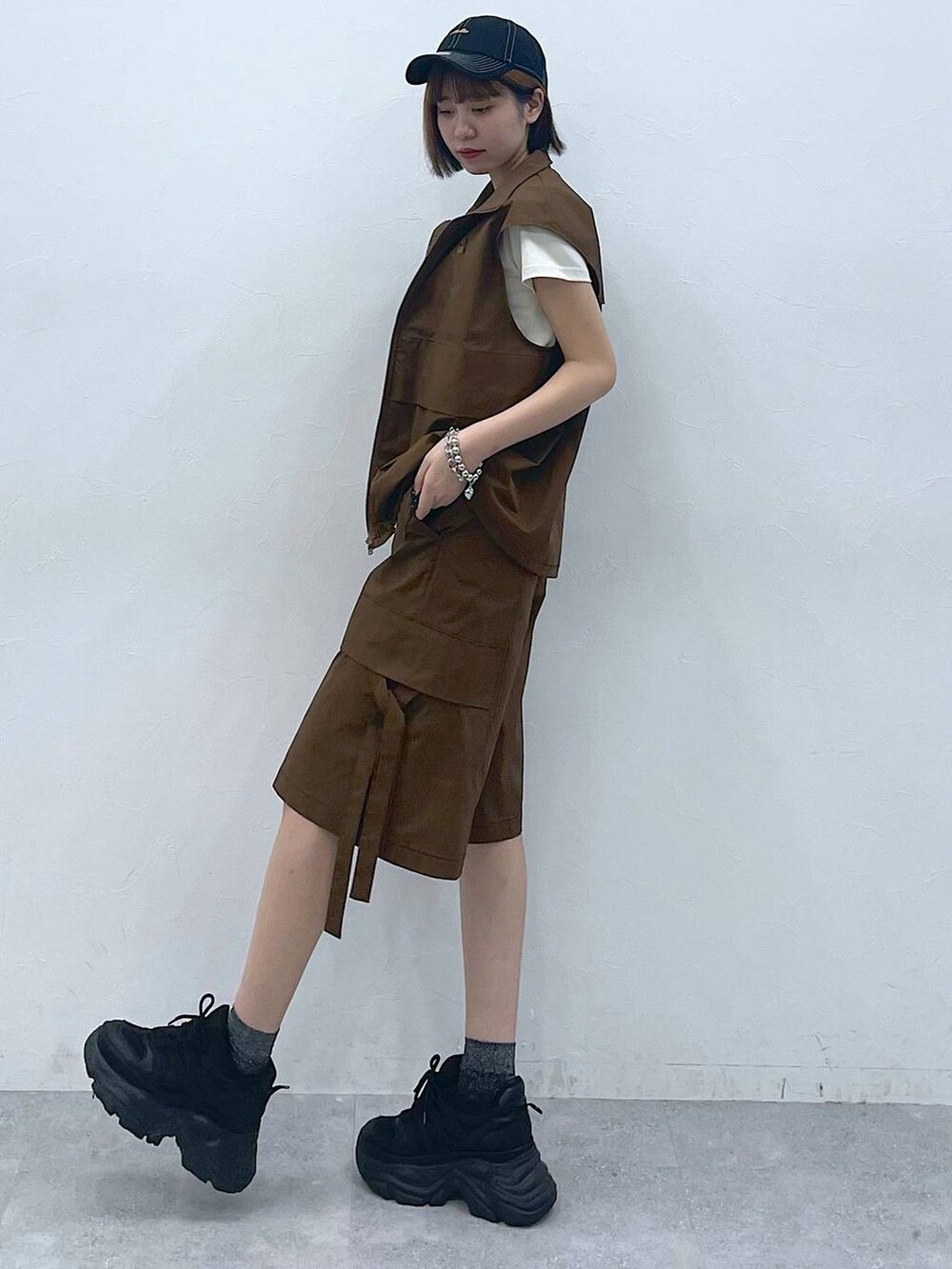 ブラック系のスニーカー、ベージュ系のTシャツ/カットソー、ブラウン系のベストを着用したレディースの夏コーディネートの5枚目の写真