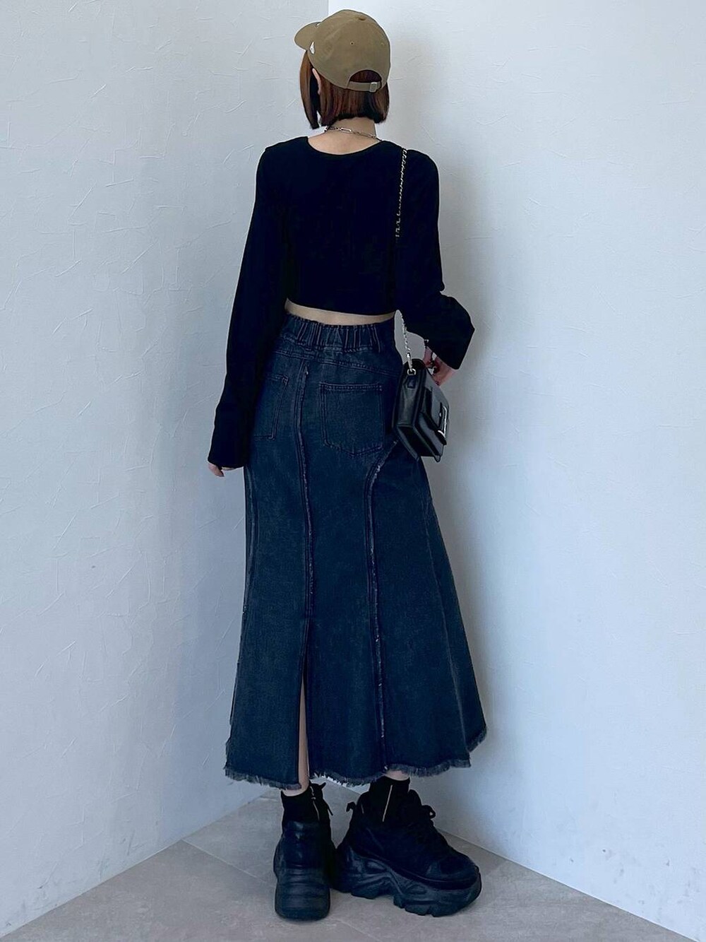 ブラック系のスニーカー、ブラック系のデニムスカート、ブラック系のTシャツ/カットソーを着用したレディースの秋コーディネートの4枚目の写真