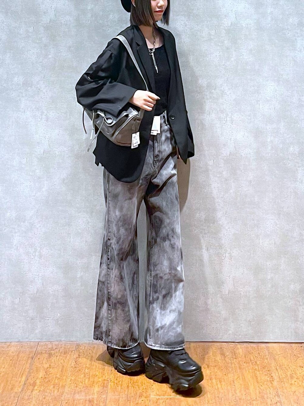 ブラック系のスニーカー、グレー系のショルダーバッグ、ブラック系のデニムパンツを着用したレディースの秋コーディネートの3枚目の写真