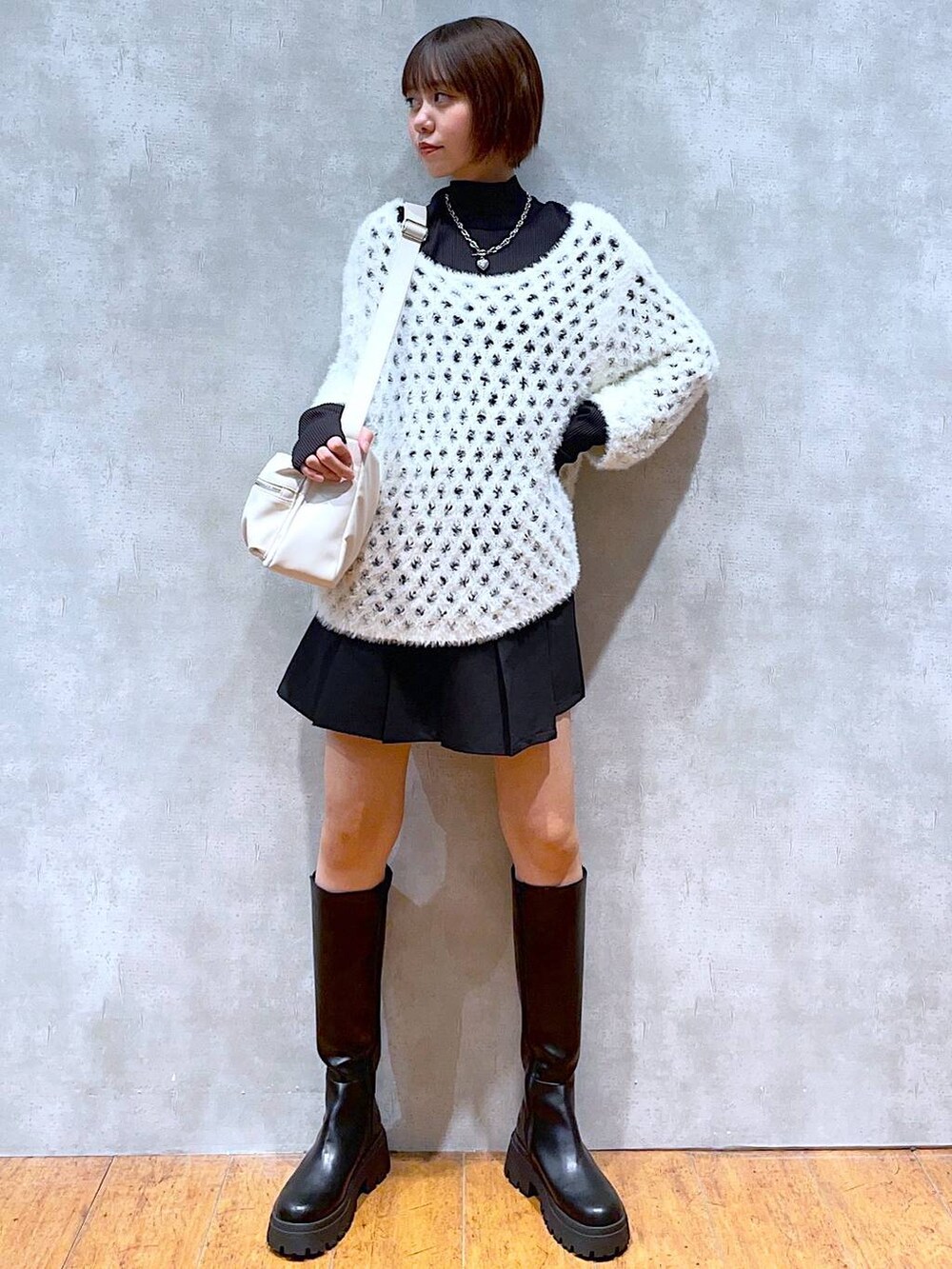 ホワイト系のショルダーバッグ、ブラック系のTシャツ/カットソー、ブラック系のブーツを着用したレディースの秋コーディネートの3枚目の写真