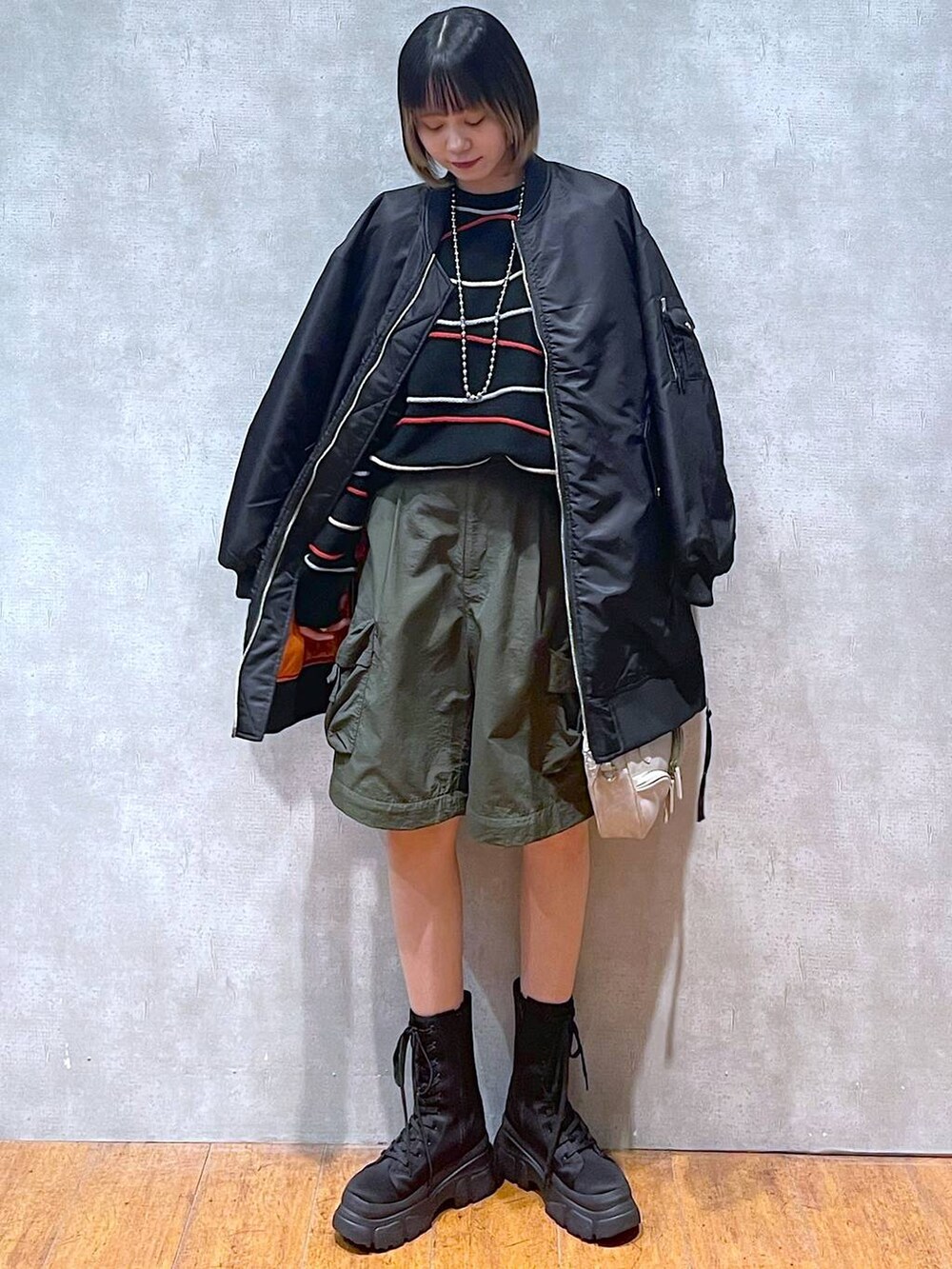 グリーン系のカーゴパンツ、ブラック系のMA-1、ブラック系のニット/セーターを着用したレディースの冬コーディネートの2枚目の写真