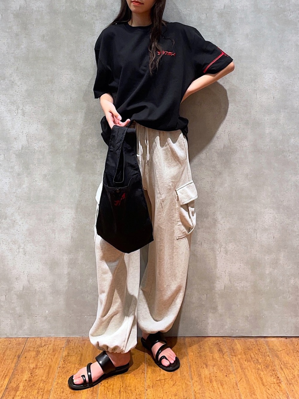 ブラック系のTシャツ/カットソー、ブラック系のエコバッグ/サブバッグ、ベージュ系のカーゴパンツを着用したレディースの夏コーディネートの2枚目の写真