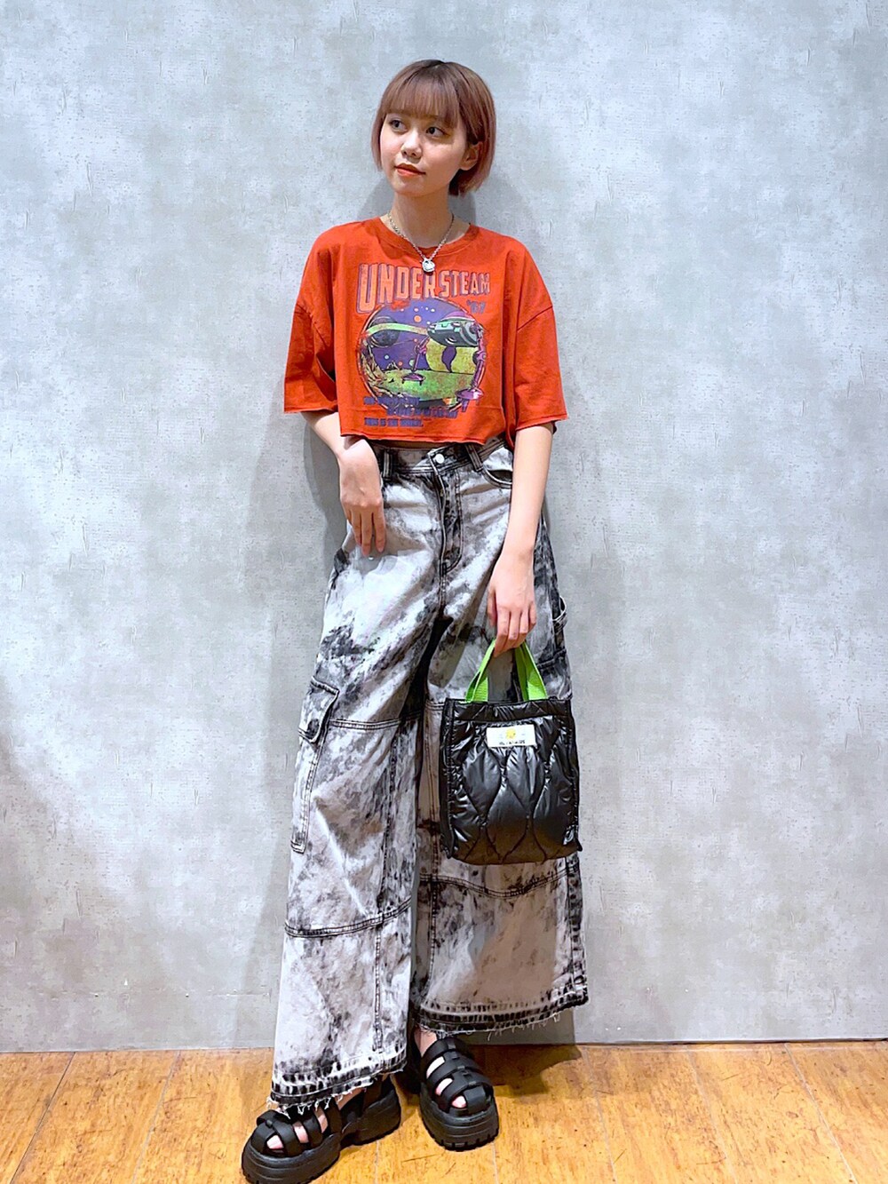 オレンジ系のTシャツ/カットソー、ブラック系のショルダーバッグ、ブラック系のデニムパンツを着用したレディースの夏コーディネートの2枚目の写真