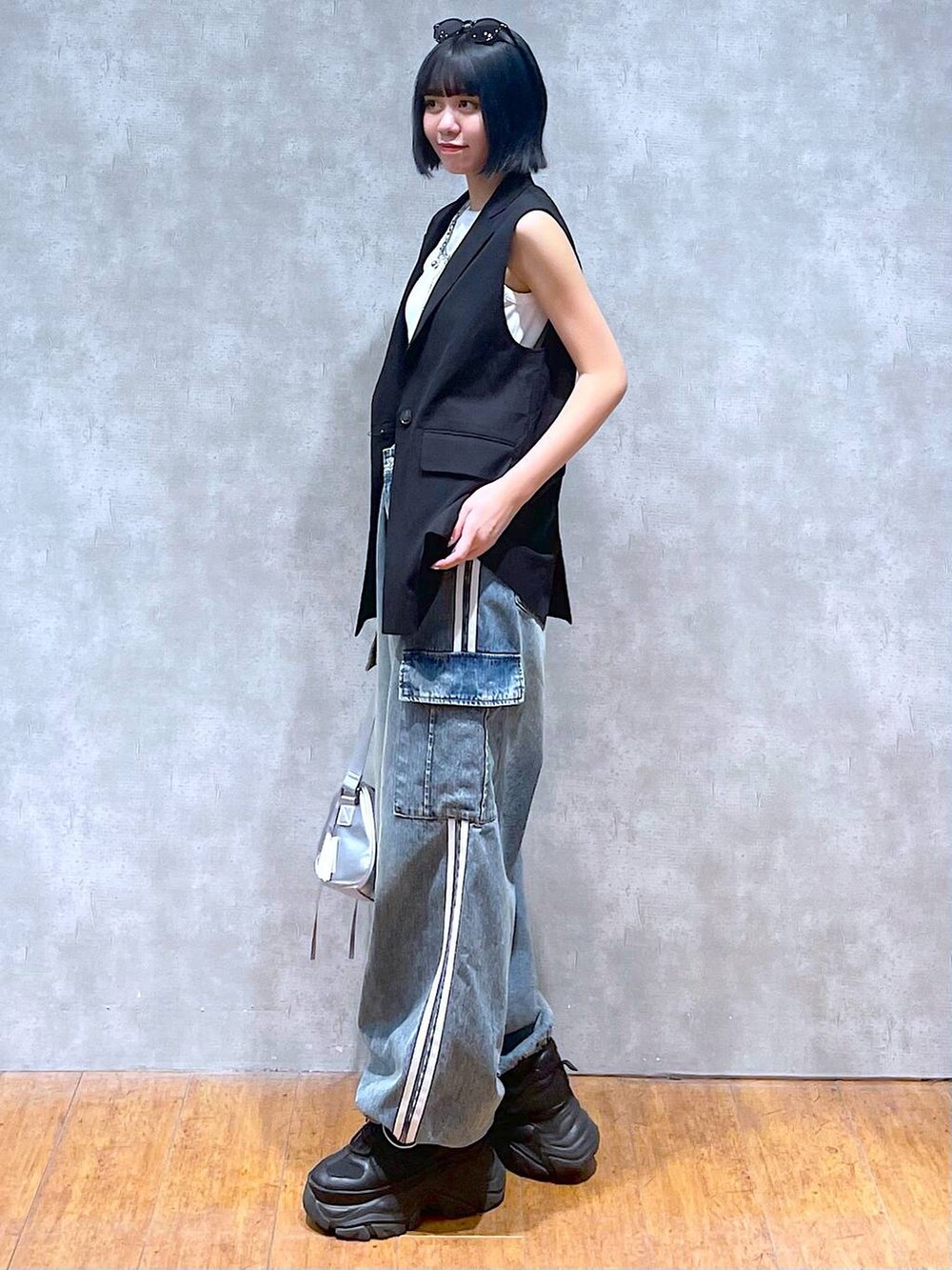 ブラック系のスニーカー、ブルー系のデニムパンツ、ホワイト系のタンクトップを着用したレディースの夏コーディネートの4枚目の写真