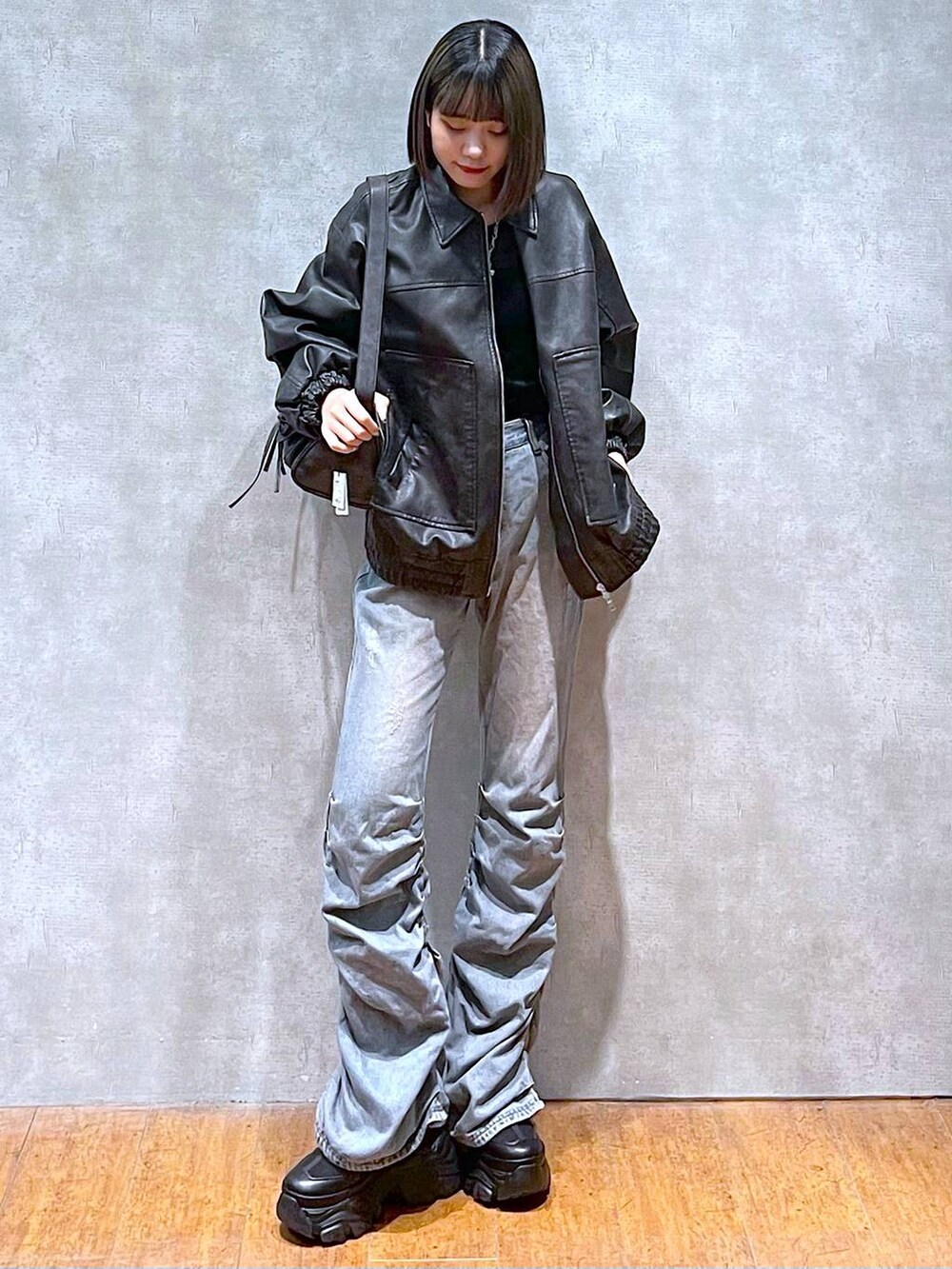 ブラック系のスニーカー、ブラック系のショルダーバッグ、ブルー系のデニムパンツを着用したレディースの秋コーディネートの2枚目の写真