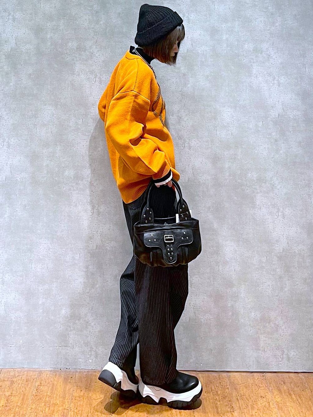 ブラック系のニット/セーター、ブラック系のデニムパンツ、ブラック系のハンドバッグを着用したレディースの秋コーディネートの2枚目の写真