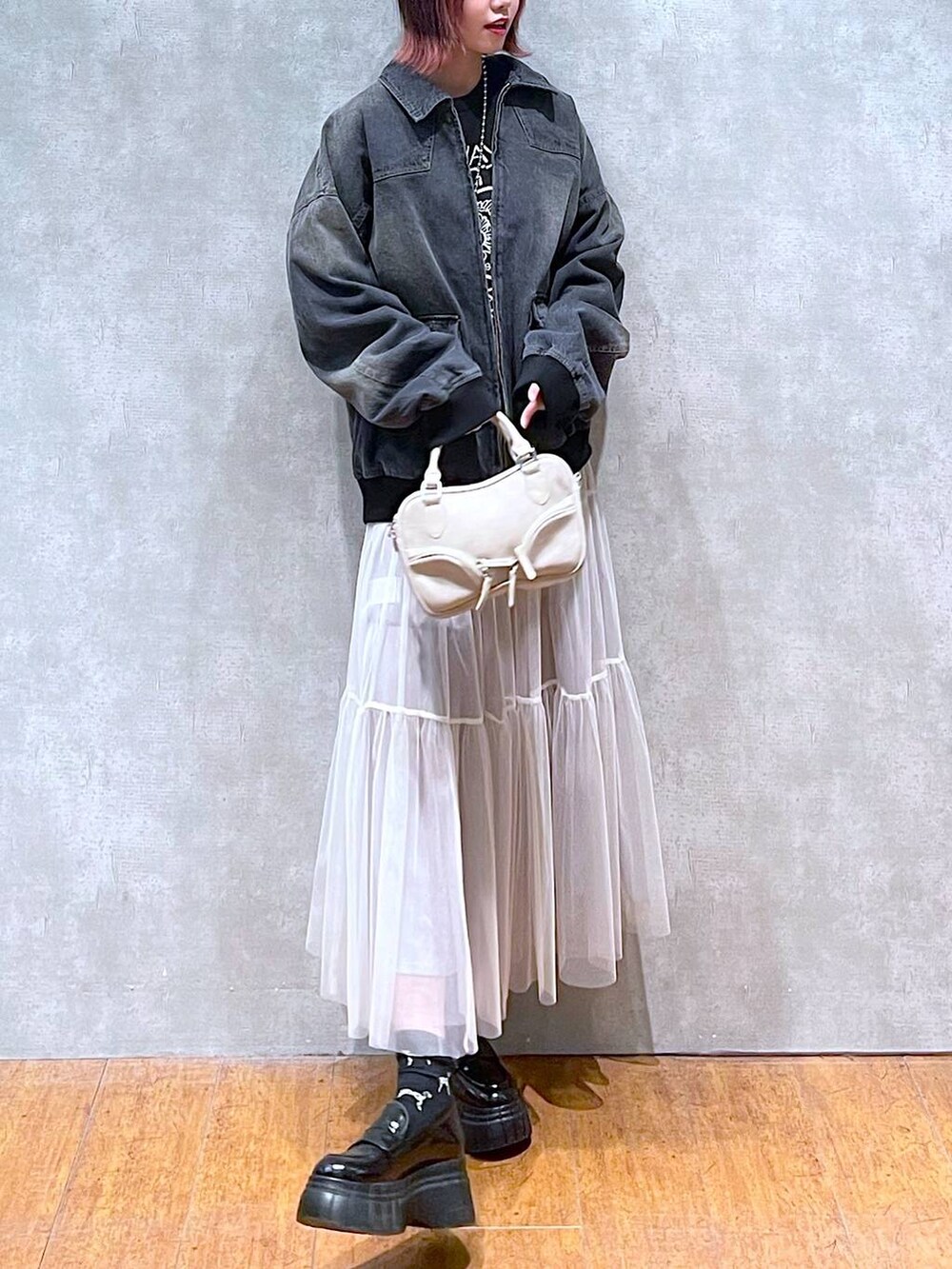 ブラック系のニット/セーター、ブラック系のデニムジャケット、ホワイト系のスカートを着用したレディースの冬コーディネートの4枚目の写真